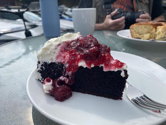 Black forest cake on a white plate at a cafe, outdoors.