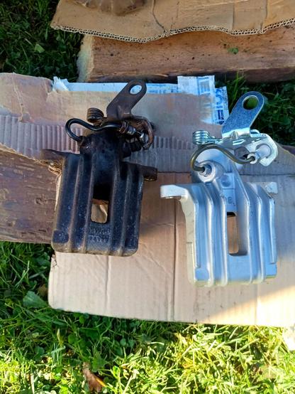 New and old brake caliper, top side. They look identical apart from rust and the new one has no VWAG logo. A little piece of metal pipe is attached to the top.