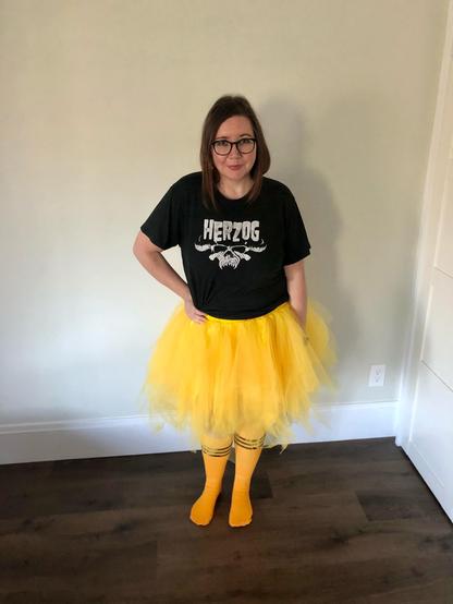 Awkward woman wearing a black Herzog/Danzig t-shirt with a yellow tutu and yellow tube socks with black stripes.