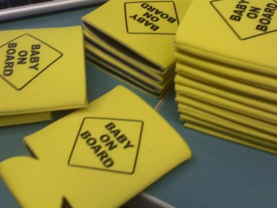 A pile of yellow beer koozies with the baby on board logo on them.