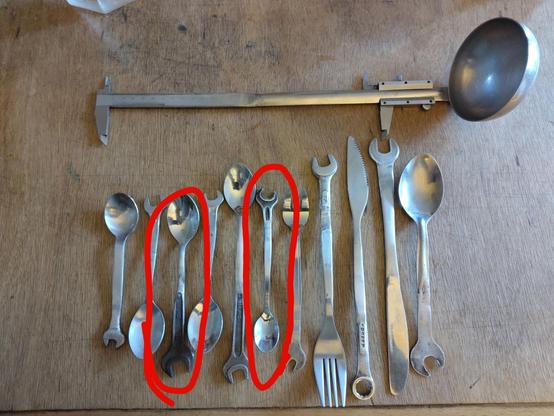 Sur une table en bois, des couverts (petites et grandes cuillères, fourchette, couteaux) qui ont chacun au bout de leur poignée un bout de clé plate, de différentes tailles et forme 
Au dessus, une louche dont le manche se termine par un pied à coulisse, dont la glissière est carrément sur la partie manche de la louche
la 3e et la 6e sont entourées en rouge