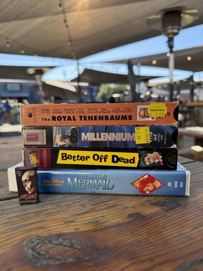 Stack of VHS tapes:
The Little Mermaid with the banned dick castle cover
Better off Dead
Millennium
The Royal Tenenbaums
