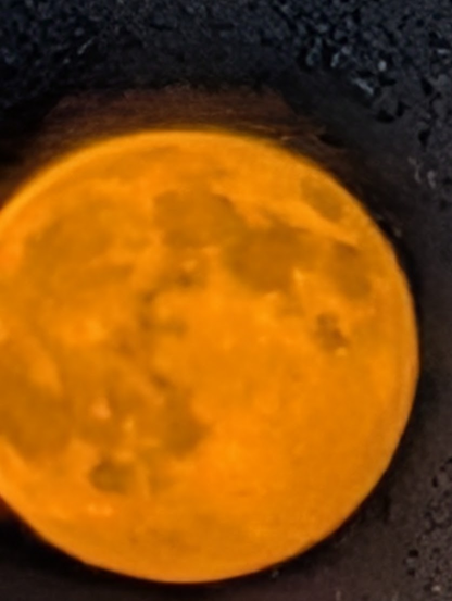 very blurry and pixelated zoomed in photo of the full moon. very orange on a black background