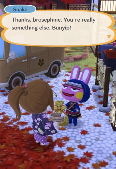 In a colorful outdoor scene, a character named Snake is interacting with another character, referred to as "brosephine," while holding a gift. Snake, dressed in a blue outfit with a sash and a headband, has a playful expression. (From Animal Crossing Pocket Camp Complete)